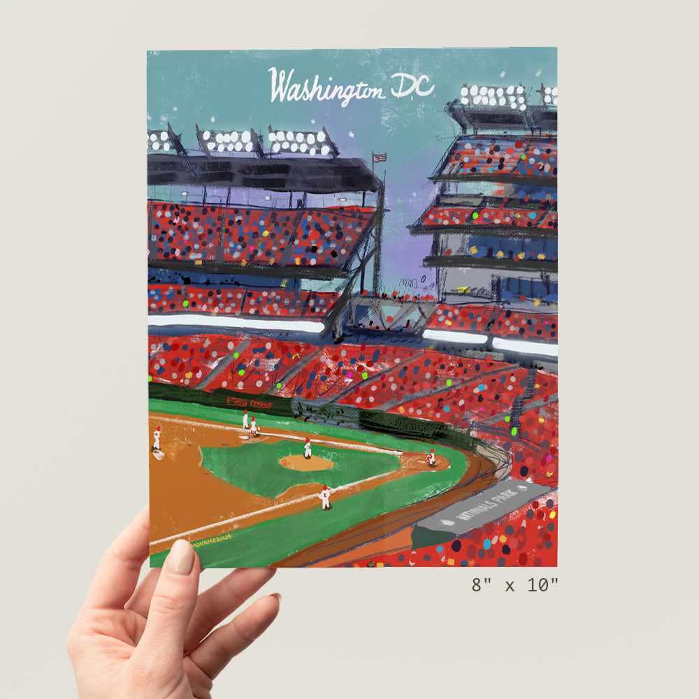 a hand holding up a picture of a baseball stadium