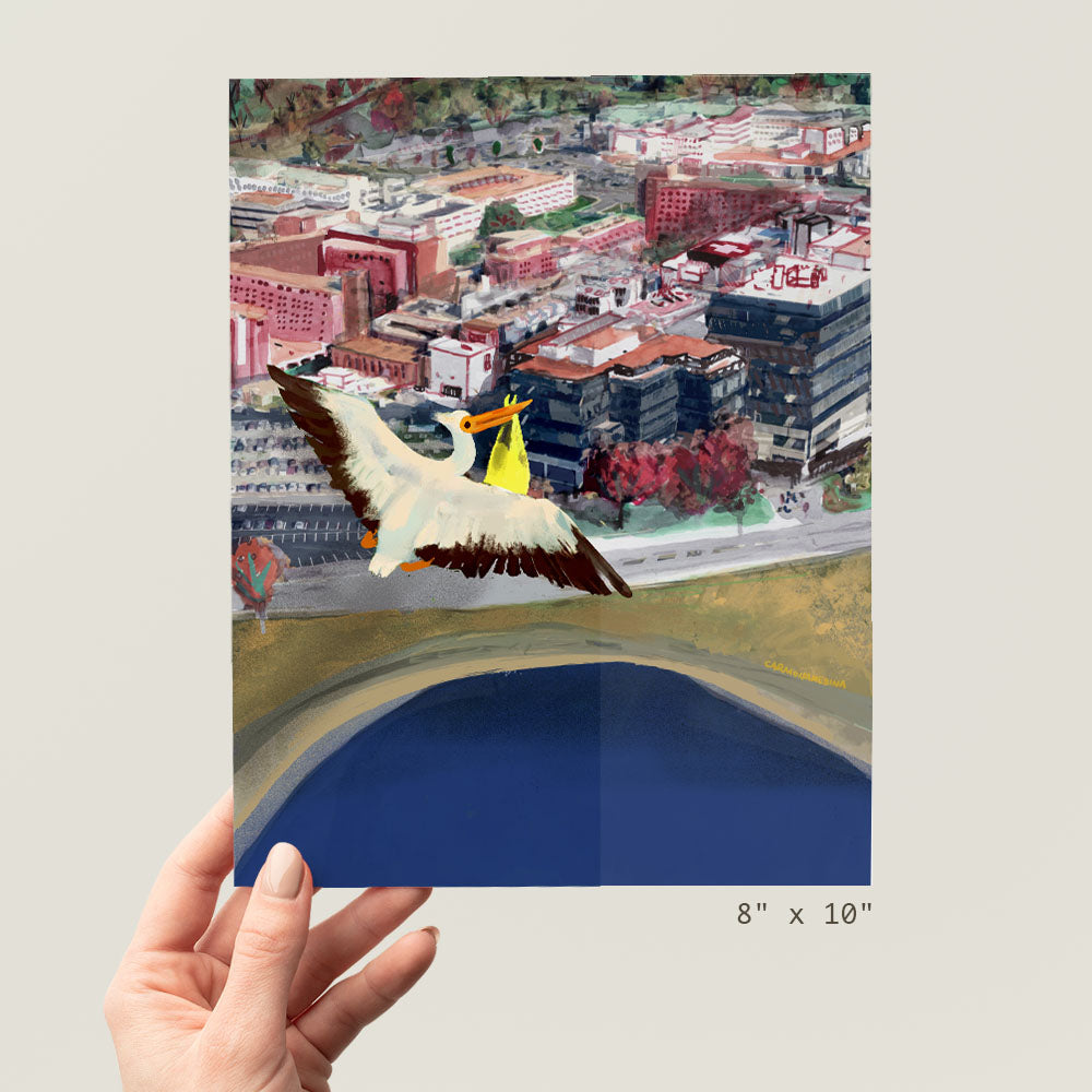 a hand holding a picture of a bird flying over a city